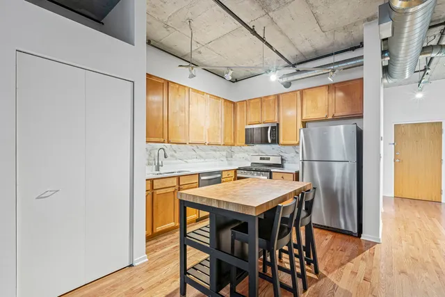 a kitchen with stainless steel appliances granite countertop a dining table chairs refrigerator a sink and dishwasher