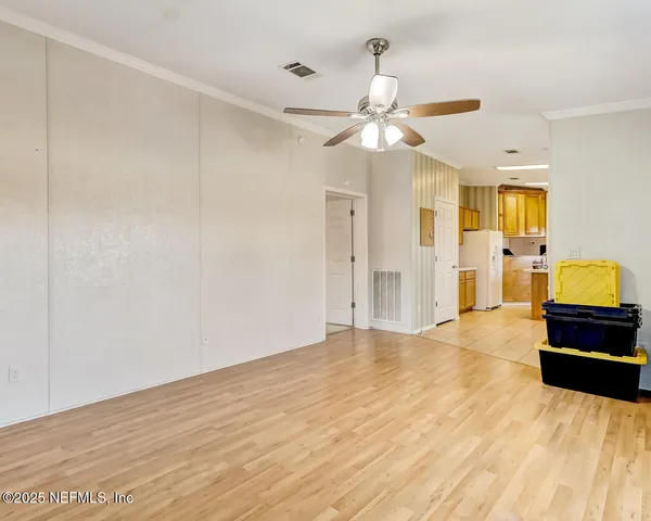 a view of a livingroom with a chandelier fan and wooden floor