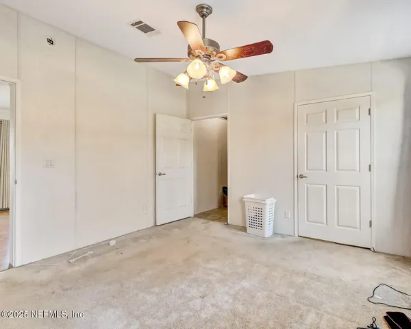 a view of an empty room with chandelier fan