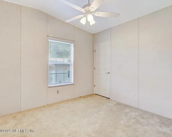 an empty room with a window and a fan