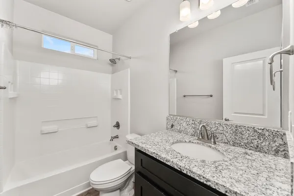 a bathroom with a granite countertop sink a toilet a mirror and shower