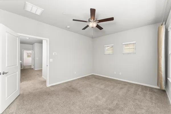 a view of a livingroom with a ceiling fan & windows