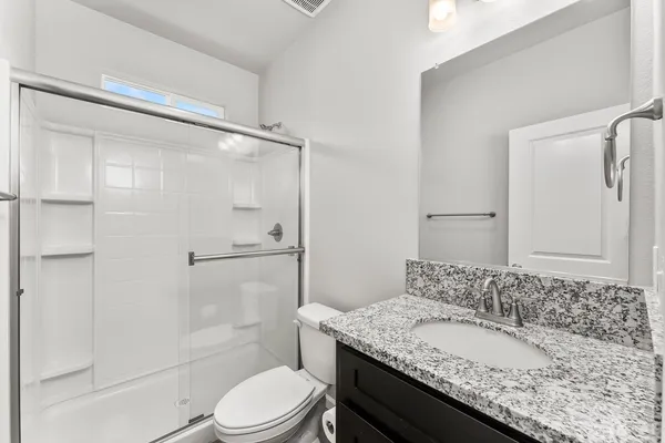 a bathroom with a granite countertop sink toilet and shower