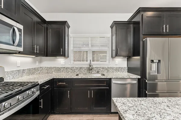 a kitchen with granite countertop a sink stove and refrigerator