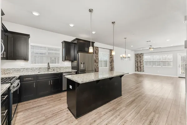 a kitchen with stainless steel appliances granite countertop a sink a stove and a wooden floors