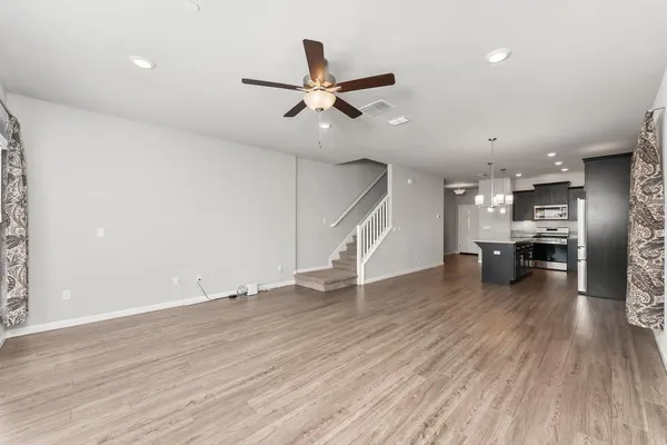 an empty room with wooden floor ceiling fan and windows
