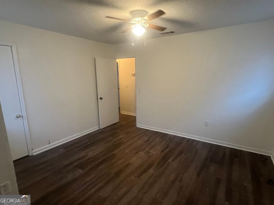 2293 Burkhalter Road Statesboro, GA 30458 - Photo 7 of 10 en empty room with wooden floor and fan