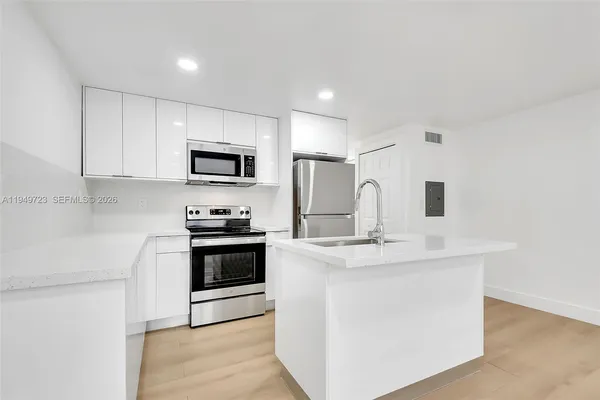 a kitchen with stainless steel appliances granite countertop a sink and a stove top oven with white cabinets