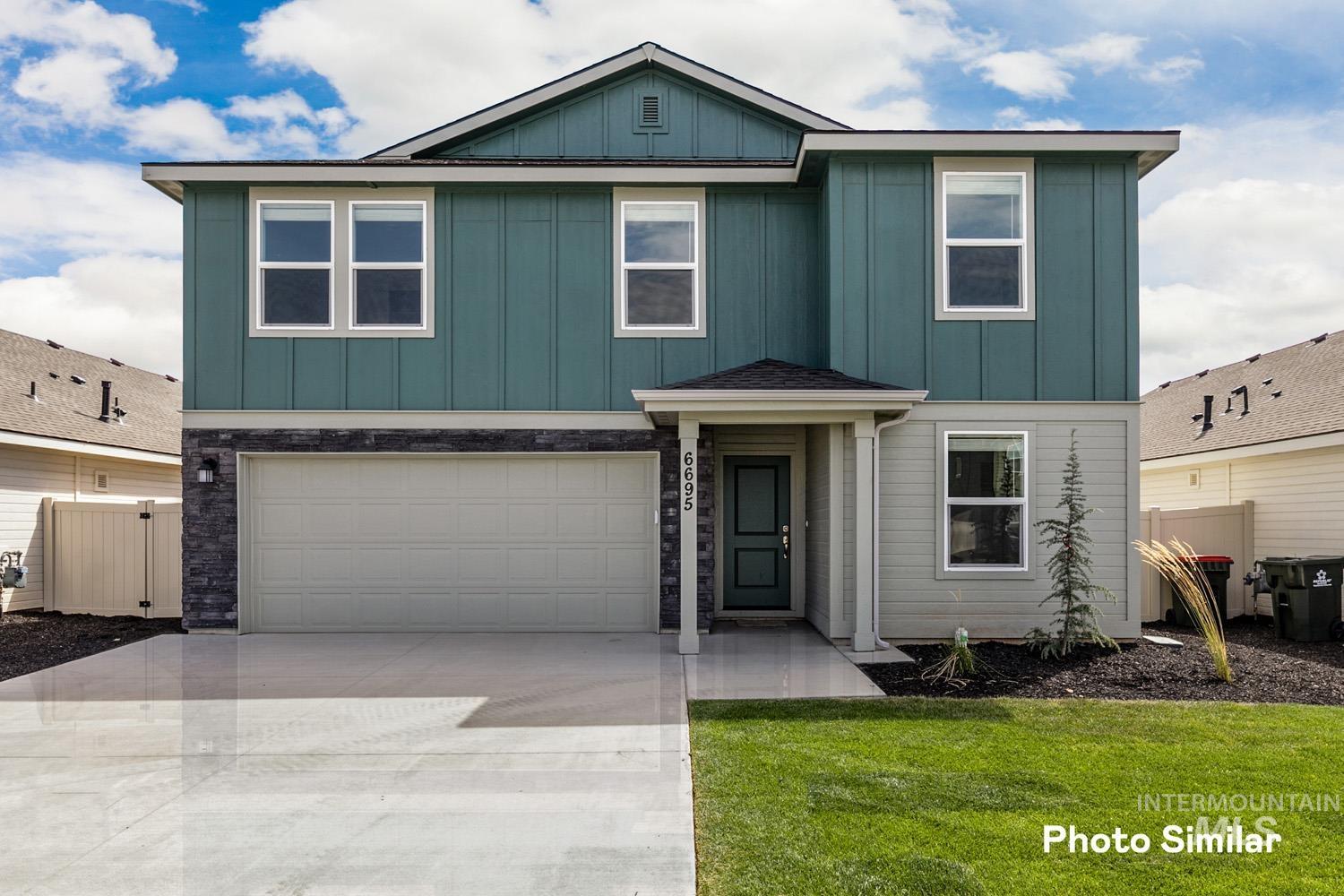View of front of property featuring board and batten siding, an attached garage, driveway, and a front yard