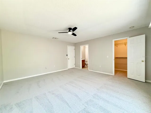 an empty room with windows and ceiling fan