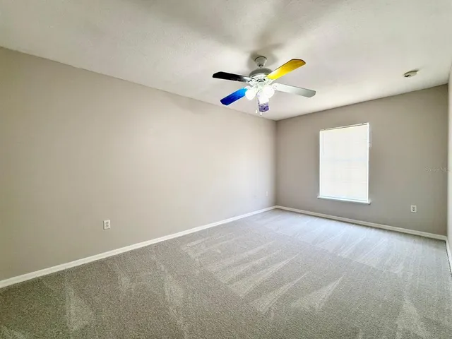 an empty room with a ceiling fan and a window