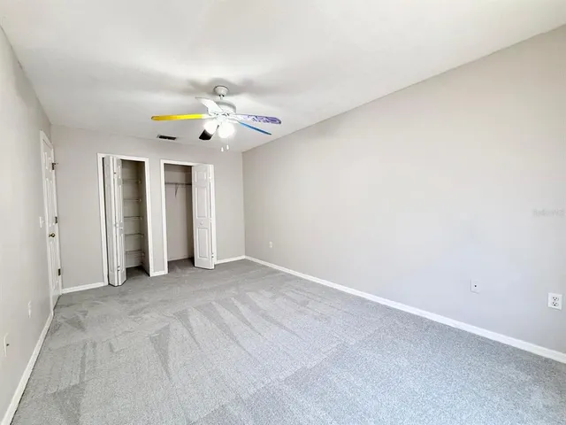 an empty room with window and ceiling fan