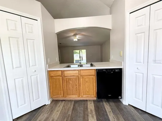 a view of kitchen with stainless steel appliances wooden floor and window