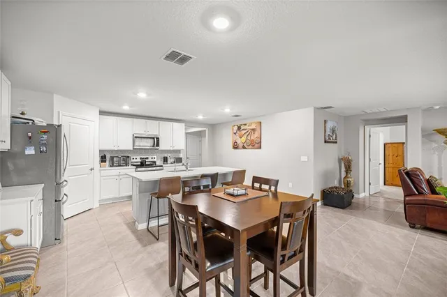 a kitchen with a dining table chairs and refrigerator