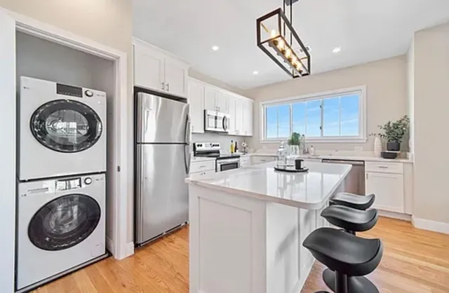 a kitchen with stainless steel appliances granite countertop a sink a stove a refrigerator cabinets and chairs