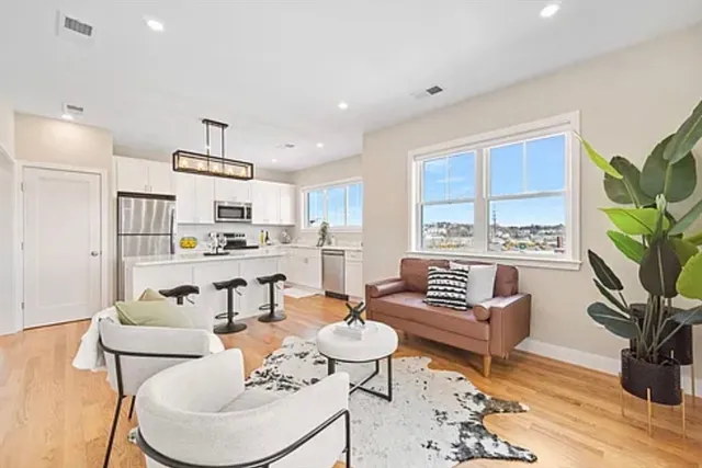 a living room with furniture kitchen view and a large window