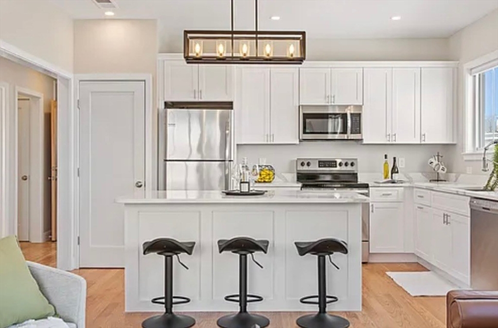 2-4 Hecla Street, Unit 1 Boston, MA 02122 - Photo 8 of 9 a kitchen with stainless steel appliances granite countertop a refrigerator and cabinets