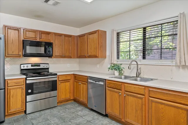 a kitchen with stainless steel appliances granite countertop a sink a stove a microwave and wooden cabinets