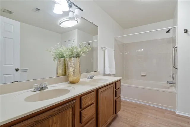 a bathroom with a sink double vanity granite tub shower and a mirror
