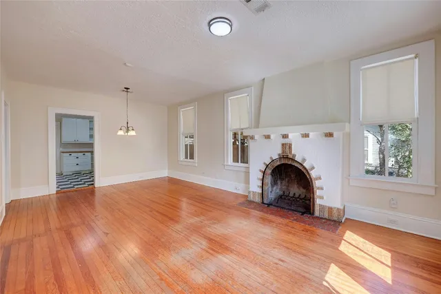 a view of empty room with fireplace and wooden floor