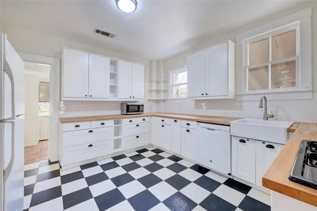 a kitchen with a checkered floor and white cabinets