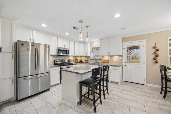 a kitchen with stainless steel appliances granite countertop a refrigerator and a stove top oven