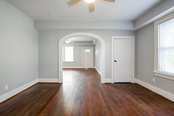 an empty room with wooden floor and windows
