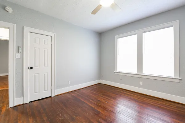 an empty room with wooden floor and windows