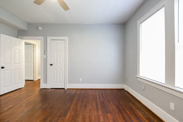 an empty room with wooden floor and windows
