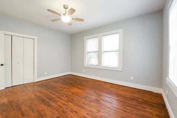 a view of an empty room with window and wooden floor