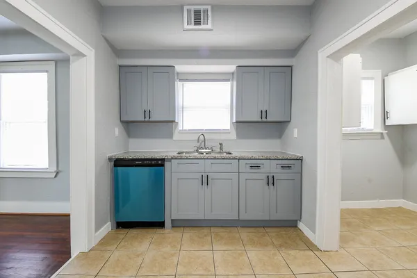a kitchen with granite countertop a sink window and cabinets