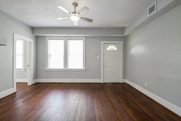 an empty room with wooden floor and windows