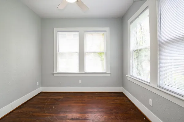 an empty room with wooden floor and windows