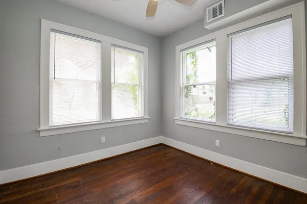 an empty room with wooden floor and windows