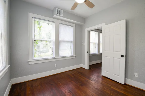 an empty room with wooden floor and windows