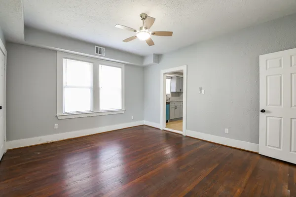 an empty room with wooden floor and windows