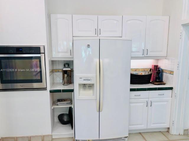 3797 El Prado Boulevard Miami, FL 33133 - Photo 11 of 26 a kitchen with stainless steel appliances white cabinets and a refrigerator