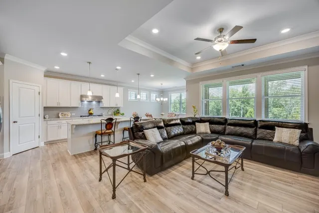 a kitchen with stainless steel appliances granite countertop a stove a sink a refrigerator a dining table and chairs with wooden floor