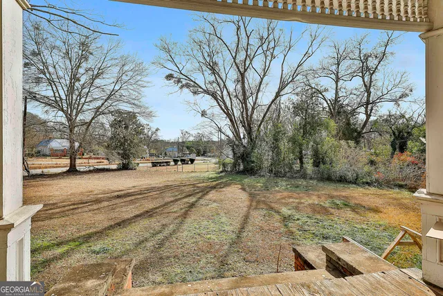a view of an empty room with wooden floor and windows