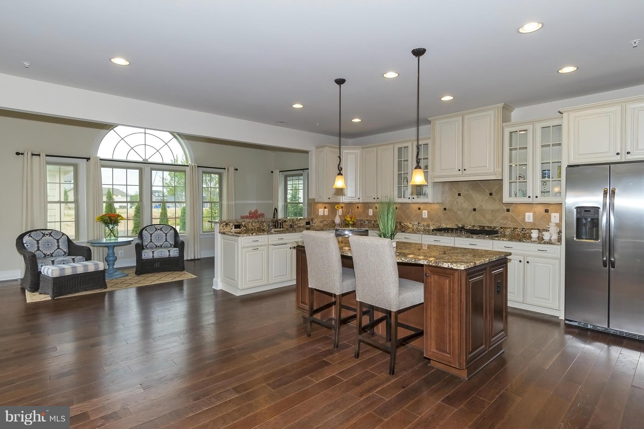 7733 Elmwood Road Fulton, MD 20759 - Photo 5 of 30 a kitchen with stainless steel appliances granite countertop a refrigerator a stove top oven a dining table and chairs with wooden floor
