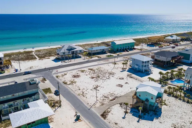 an aerial view of ocean and residential houses with outdoor space
