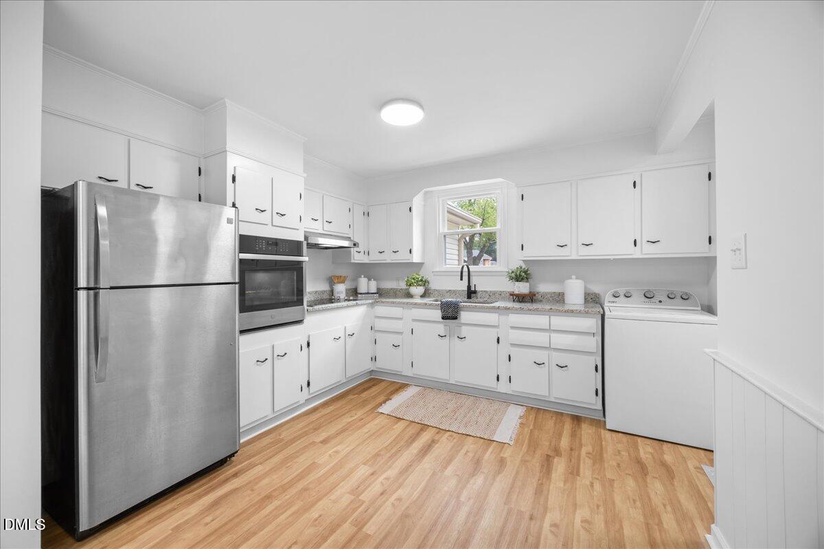 3437 Apache Drive Raleigh, NC 27609 - Photo 4 of 33 a kitchen with white cabinets stainless steel appliances and wooden floor
