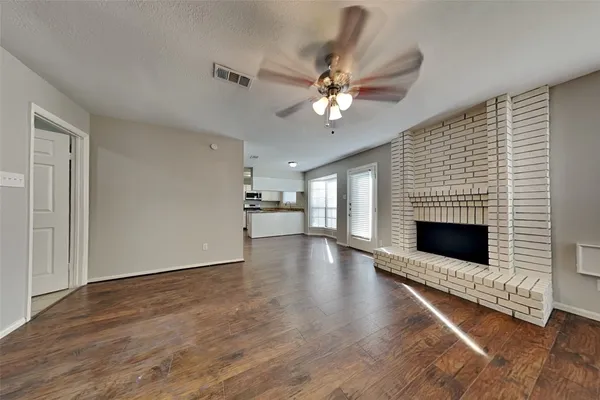an empty room with wooden floor fireplace and windows
