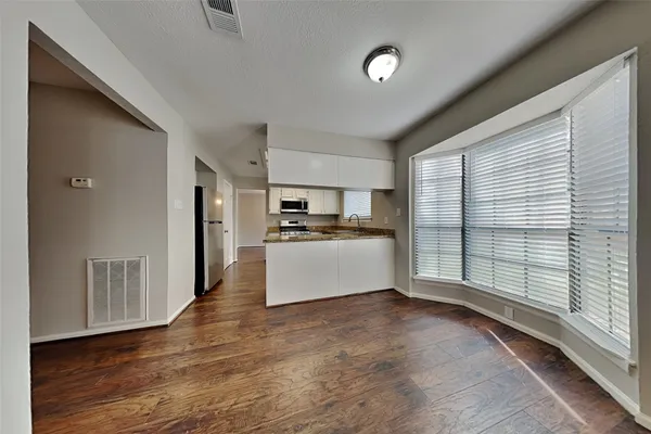 a view of kitchen with stainless steel appliances wooden floor and window