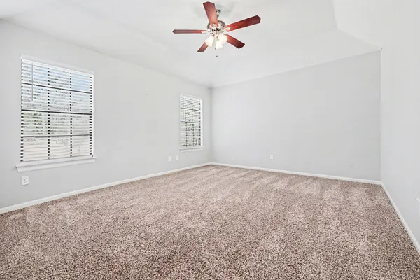 an empty room with windows and fan