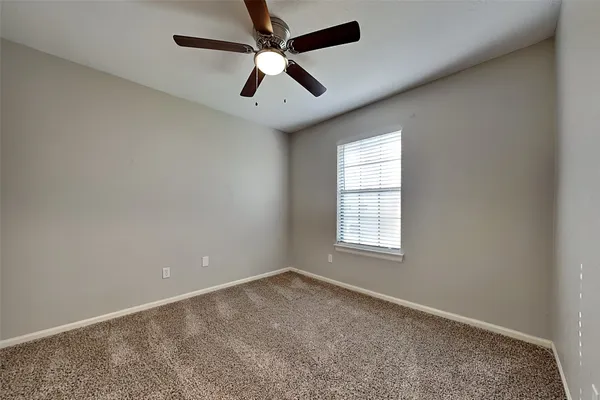an empty room with a window and a fan