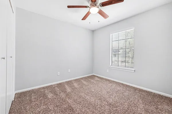 an empty room with chandelier fan and windows