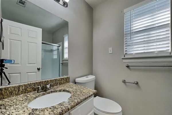 a bathroom with a granite countertop toilet sink and mirror