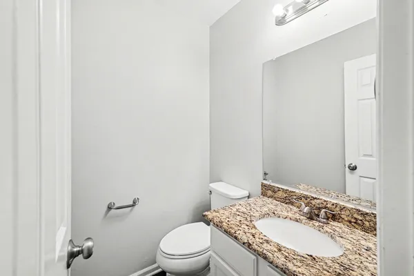 a bathroom with a granite countertop sink a mirror and a toilet