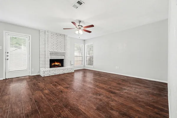 an empty room with windows and fireplace